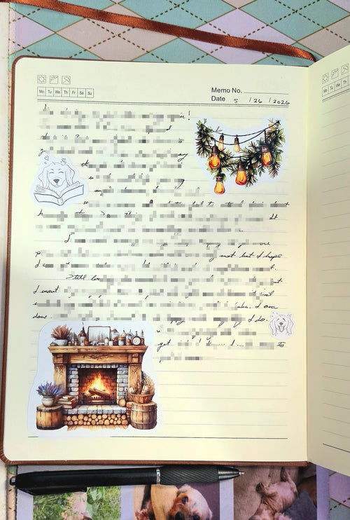 Notebook with decorative stickers featuring a fireplace and Christmas tree on a checkered tablecloth background.