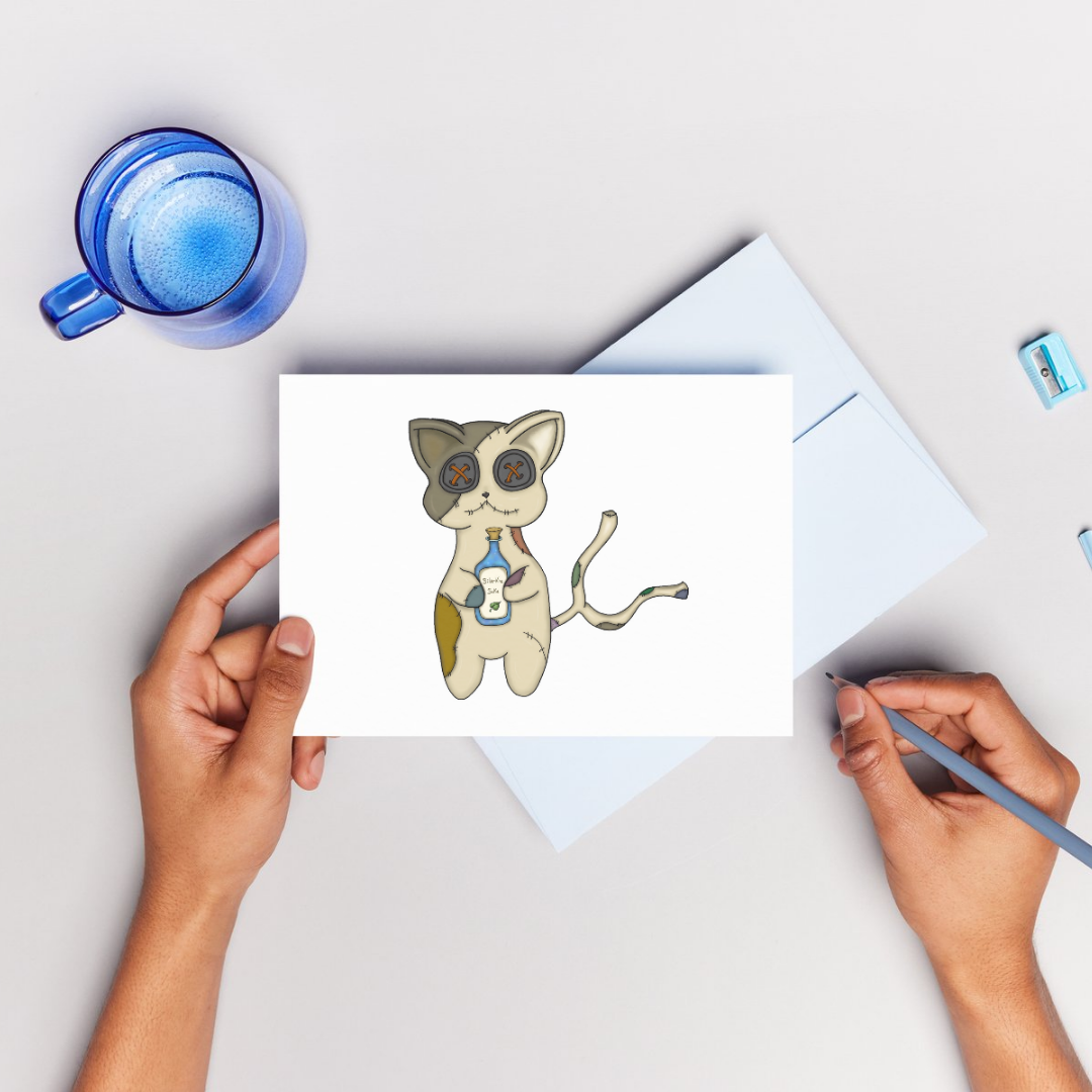 Person holding a card with a cat illustration on a light surface with a blue mug.